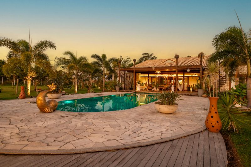 Tranquil backyard with a pool, palm trees, and a cozy house at sunset, ideal for relaxation